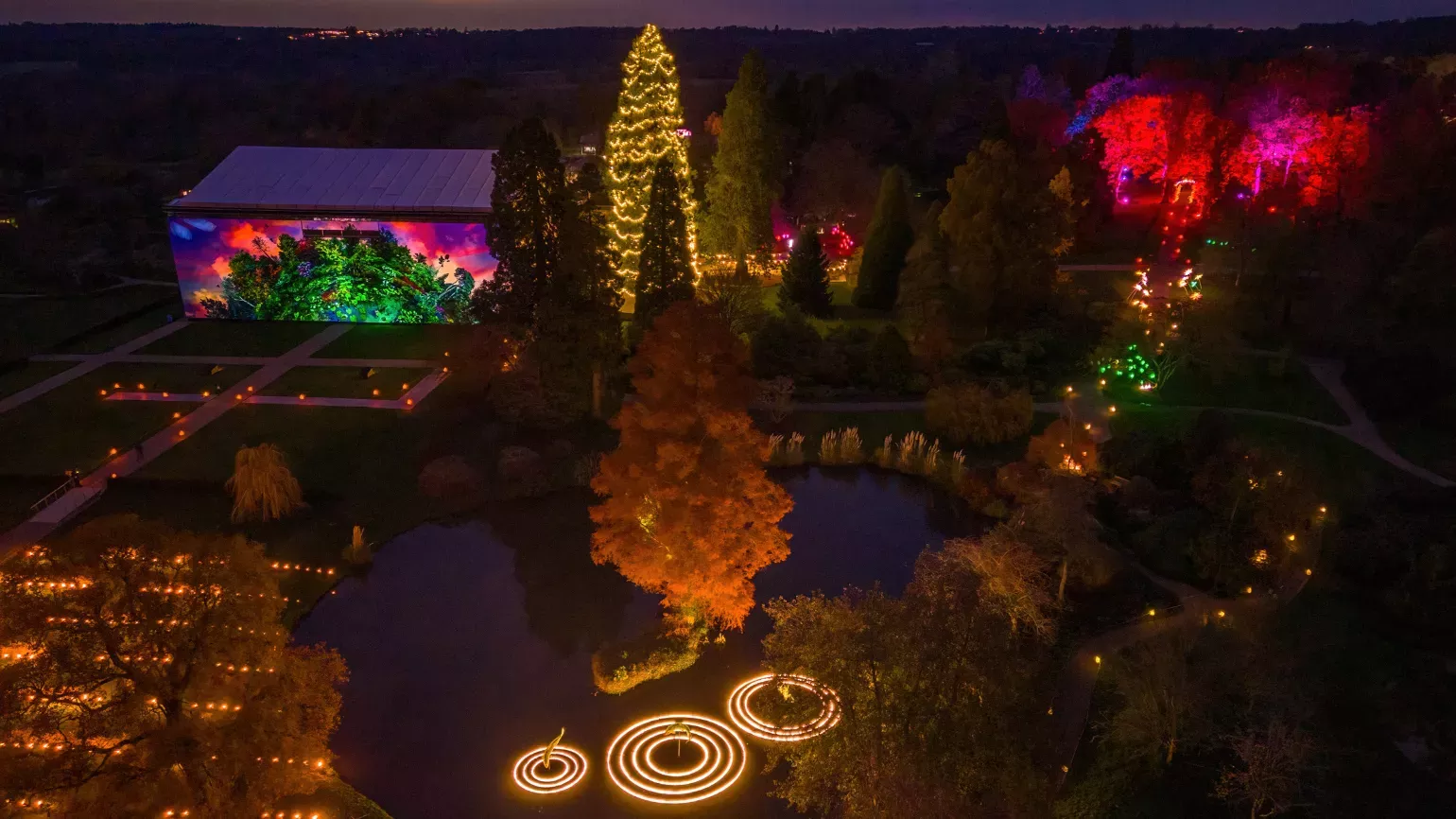 Glow Wild from above in 2023, showing Wakehurst House, the Christmas lights and the Christmas tree low Wild from above in 2023, showing Wakehurst House illuminated with a light installation, the Christmas lights and the Christmas tree