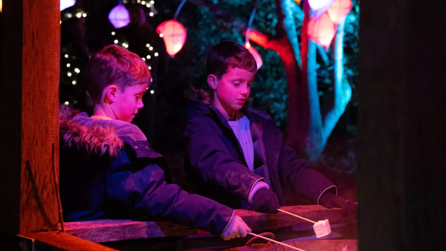 Two children enjoying roasting marshmallows over a Glow Wild's fire pit Two children enjoying roasting marshmallows over a Glow Wild's fire pit