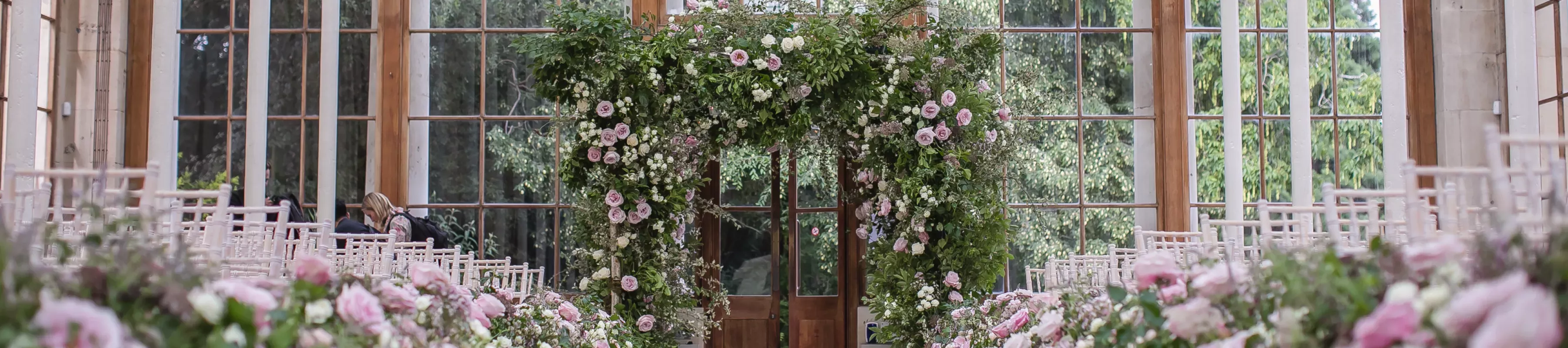 Hire a venue at Kew © Lara Arnott White chairs and colourful pink flowers adorning the Nash Conservatory at Kew