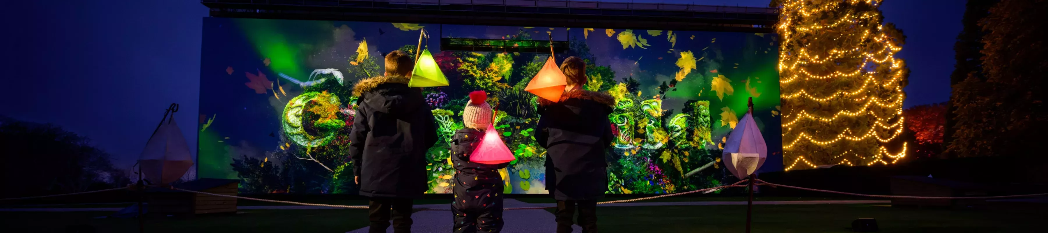 Planet Wakehurst at Glow Wild 2023, Jim Holden © RBG Kew Large colourful projection and Christmas tree at Wakehurst