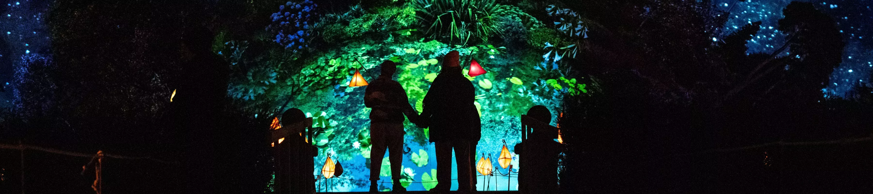 A family stands in front of lanterns and light installations at Glow Wild
