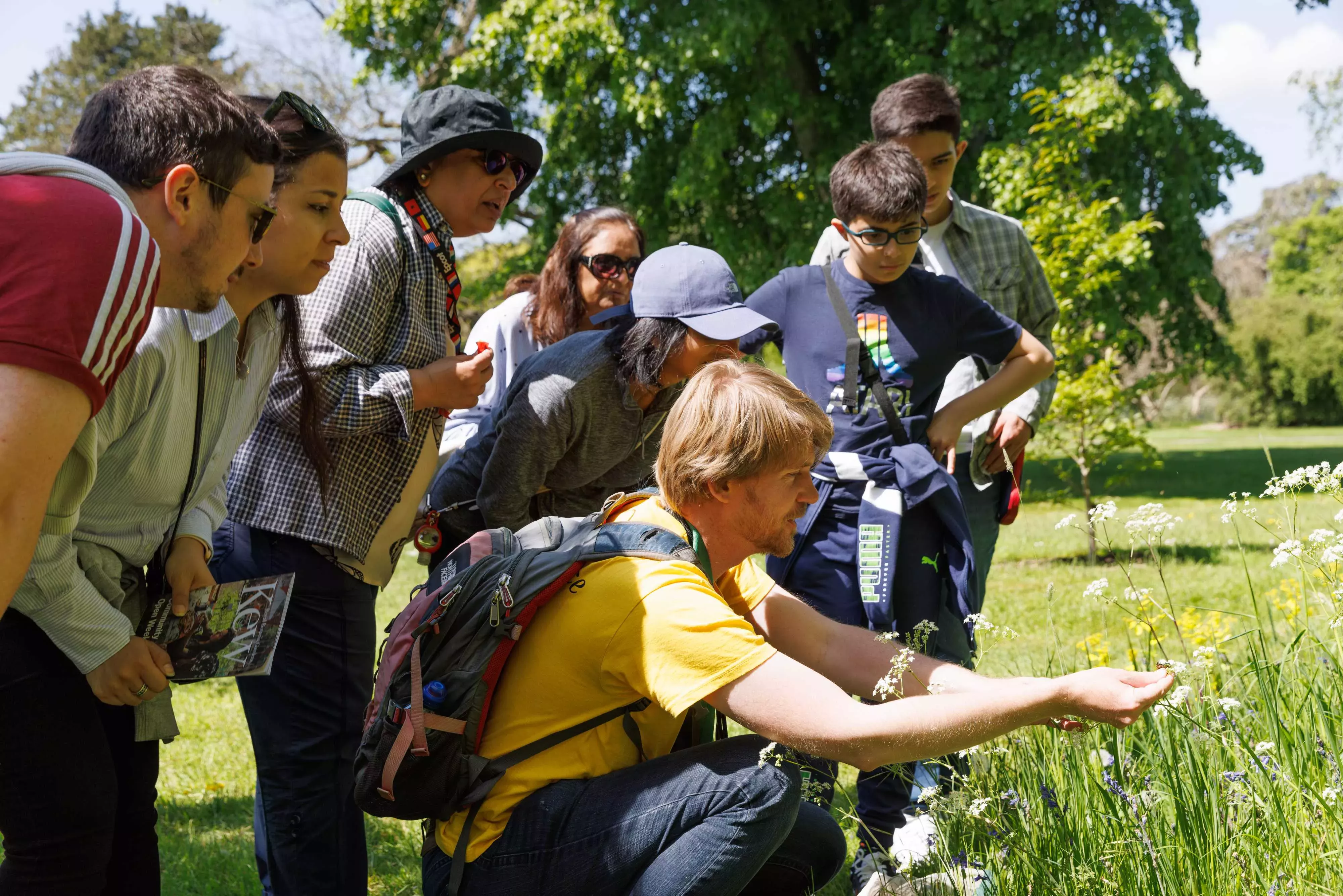 Young people gathered around a Kew scientist inspecting plants and pollinators