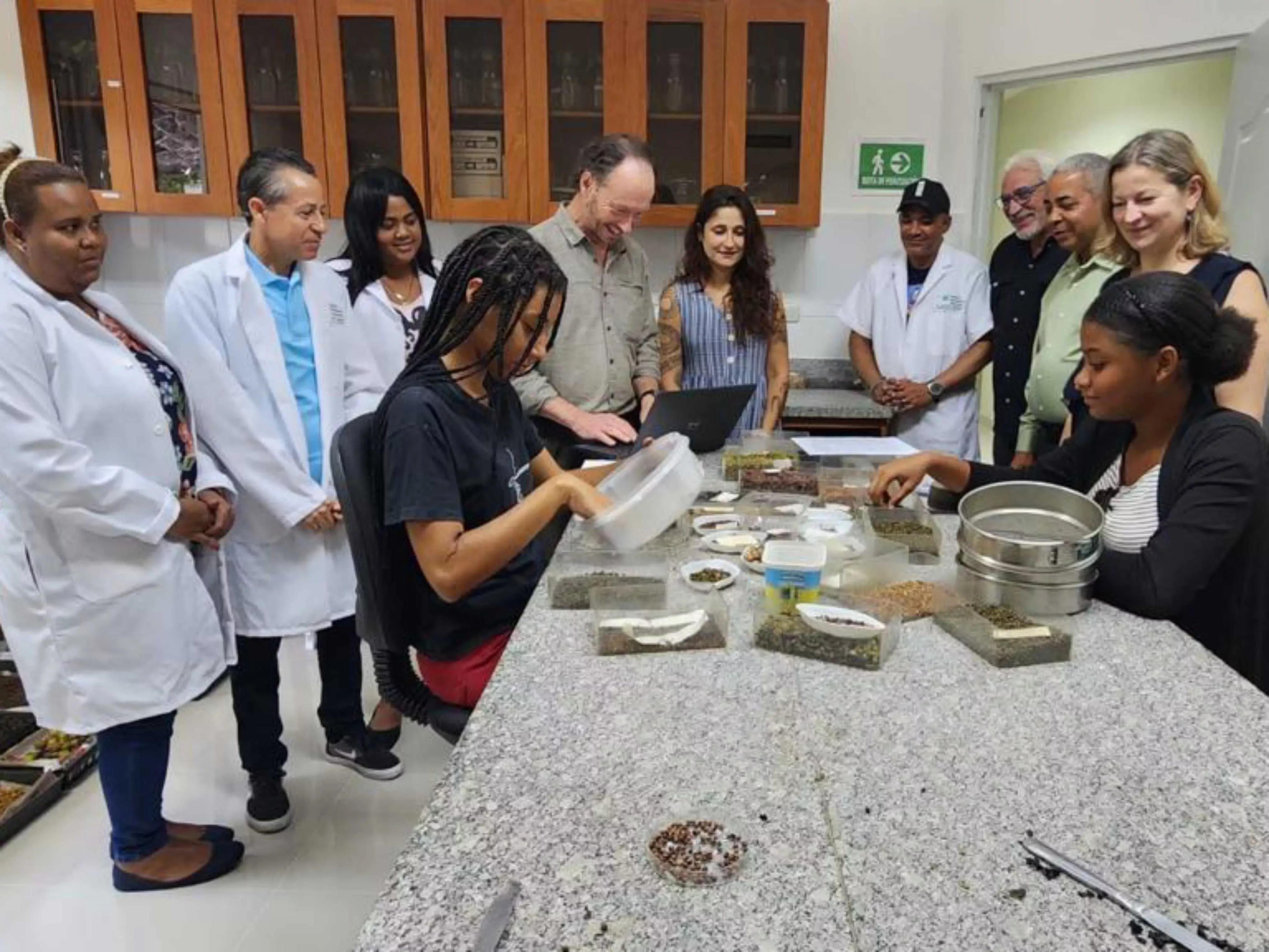Researchers observe lab researchers working on seed processing