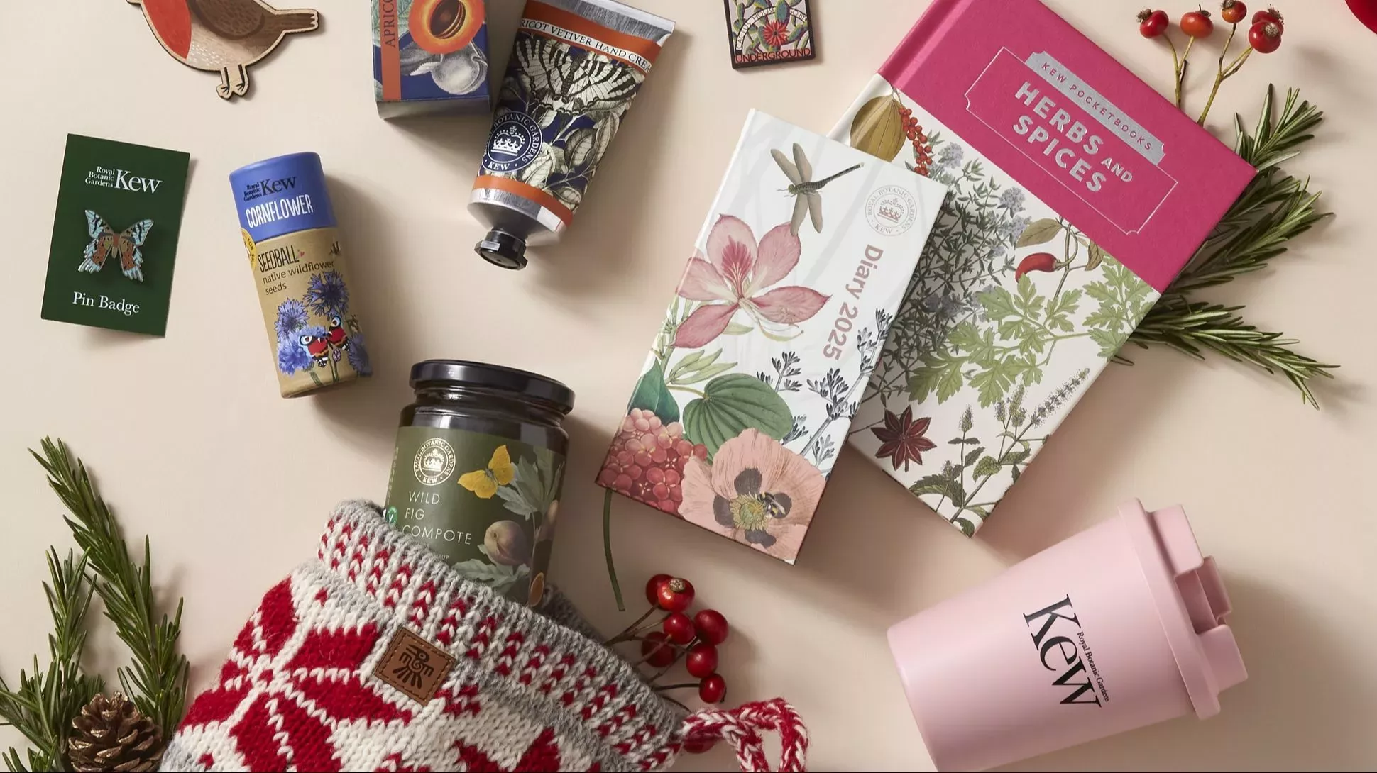 Kew shop stocking fillers Selection of stocking filler gifts from Kew including, handcream, seedballs, a pin badge, a book about herbs and spices, a 2025 diary and some festive foliage
