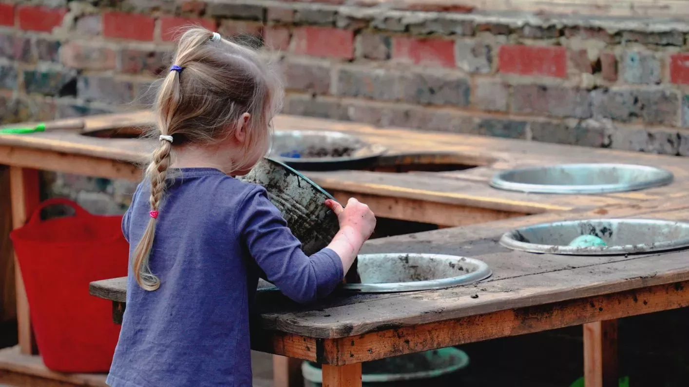 Mud Kitchen at Wakehurst, Visual Air © RBG Kew A young girl tips a bowl of mud into another bowl